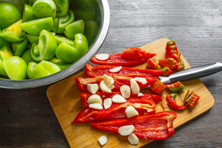 How to Prepare Bell Peppers for Kimchi Paste A red bell pepper being cored and cut on a wooden board.