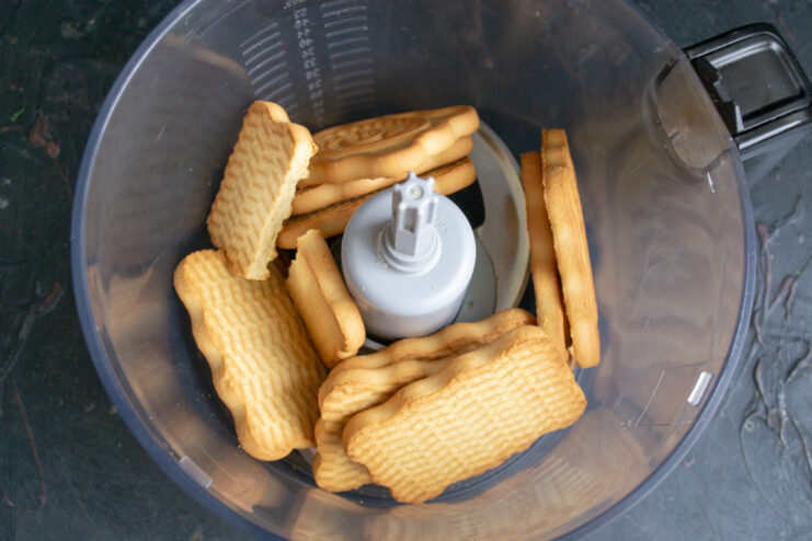 Step 1: Crushing shortbread cookies in a blender to make the cake base. Shortbread cookies inside a blender bowl, ready to be crushed for the crust.
