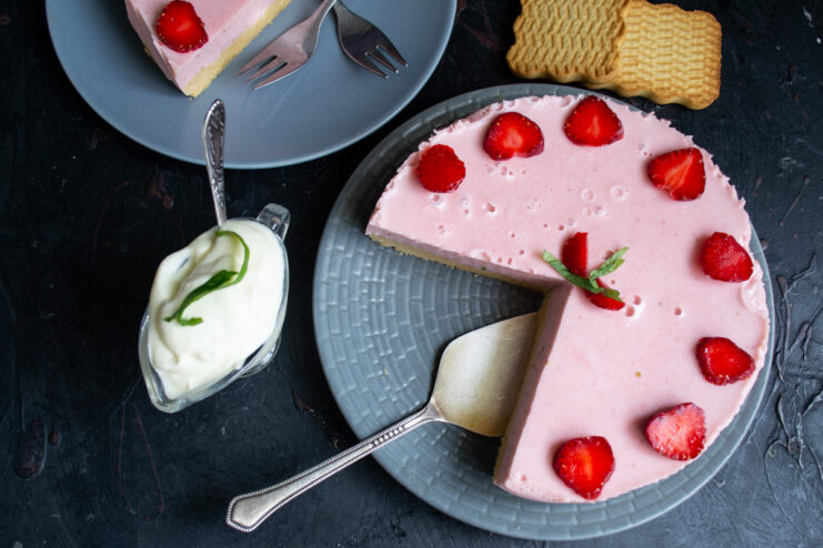 Serving the delicious no-bake strawberry cake with whipped cream. A slice of the finished no-bake strawberry cake served with a dollop of whipped cream.