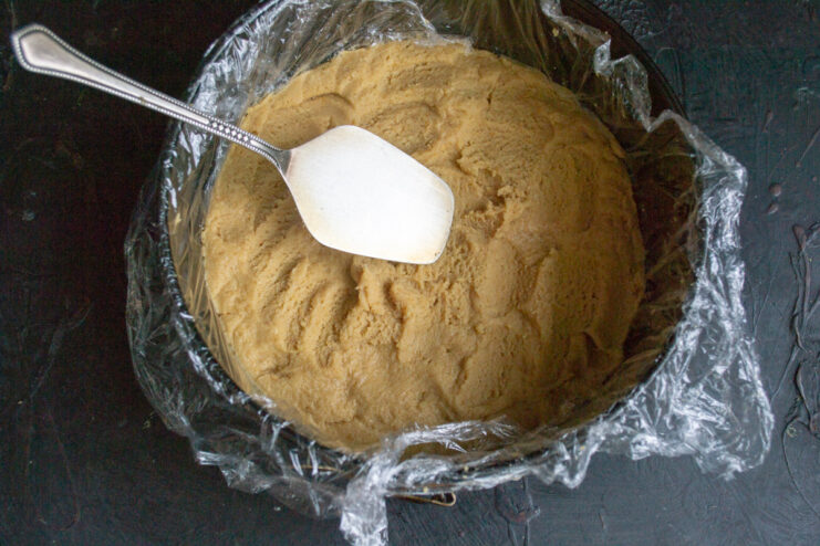 Step 4: Pressing the cookie dough into a springform pan. Pressing the cookie crumb mixture into the bottom of a lined springform pan.