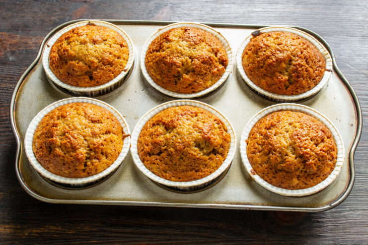 Bake the muffins in a preheated oven for 24-26 minutes until golden brown A muffin tin filled with batter being placed into a hot oven to bake.