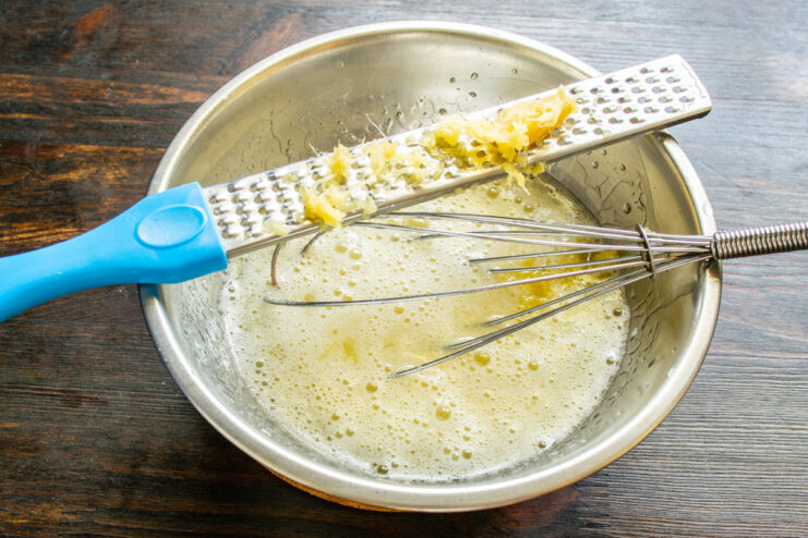 Freshly grated ginger adds a warm, spicy note to the muffins A hand grating fresh ginger root on a fine metal grater.