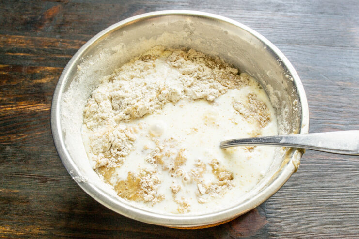 Adding milk or light cream to create a moist and tender muffin batter Pouring milk from a measuring cup into the bowl of muffin batter.