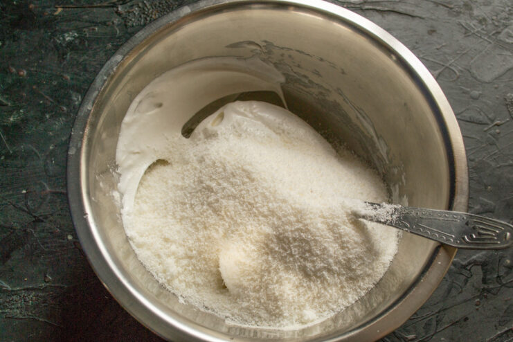 Mixing in Shredded Coconut to Form the Cookie Dough Adding shredded coconut to the meringue and flour mixture to form the cookie dough.