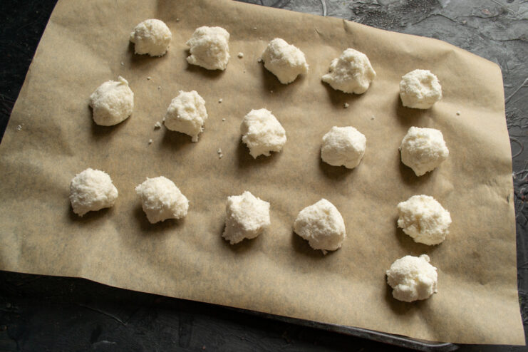 Forming Small Cookies with a Teaspoon Using a teaspoon to scoop and form small balls of coconut cookie dough.