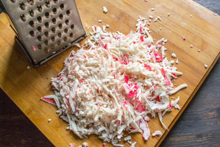 Pro Tip: Use Frozen Crab Sticks for Easy Grating - The secret to the perfect cutlet texture. Grating frozen crab sticks on a box grater to prepare the mixture for cutlets.