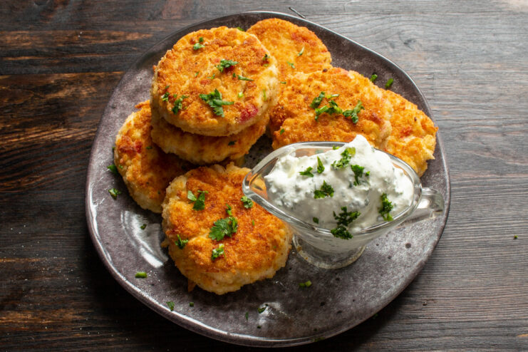 Ready to Serve: Hot Crab Stick Cutlets with Creamy Sauce - A delicious and visually appealing dish. A final dish of hot crab stick cutlets served on a plate, drizzled with a creamy white sauce and garnished with herbs.
