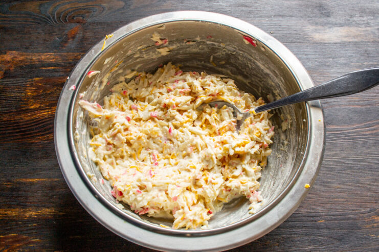 Combining All Ingredients for the Crab Stick Cutlets - Mix until everything is well incorporated. Mixing the crab stick, egg, smetana, flour, and cheese mixture in a bowl.
