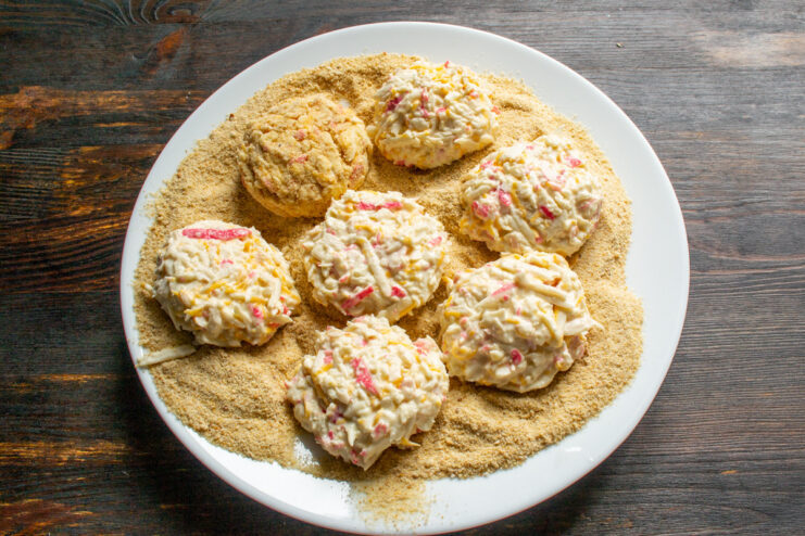 Preparing for Frying: Coating the Cutlets in Breadcrumbs - The first step to a crispy exterior. Shaped raw crab stick cutlets placed on a plate covered with breadcrumbs.