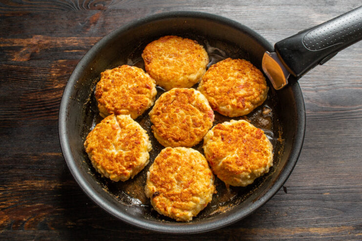 Frying to Perfection: Flipping the Cutlets - Cook until both sides are golden brown and crispy. Crab stick cutlets being flipped in a hot frying pan to cook the other side.