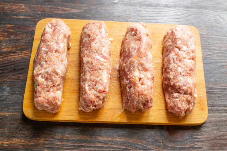 A bowl of seasoned ground meat divided into four equal portions.