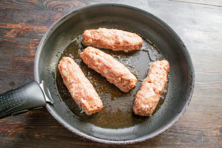 A heavy-bottomed skillet being heated on a stove.