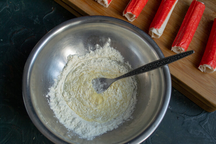 Flour being mixed into a whisked egg to create a thick batter.
