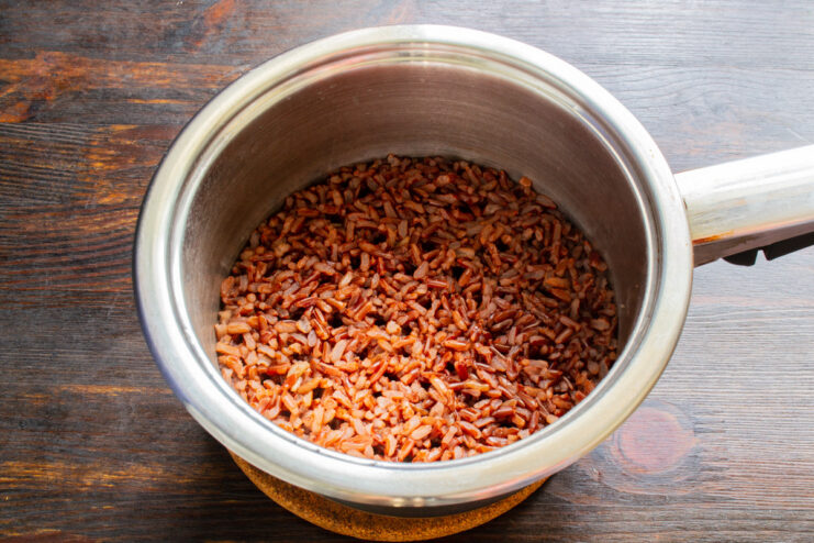Simmering red rice on the stove for the perfect texture. A saucepan with red rice simmering on a stove with a low flame.