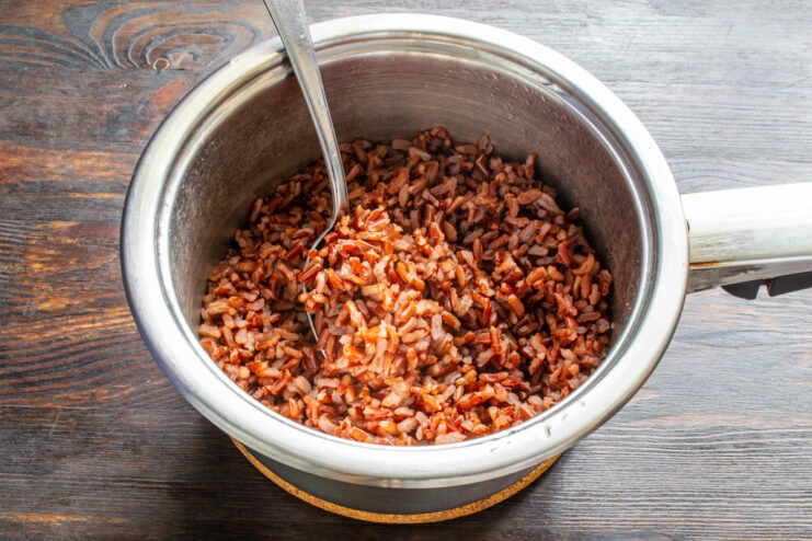 The secret to perfectly fluffy and non-sticky red rice. A close-up of fluffy, cooked red rice in a saucepan.
