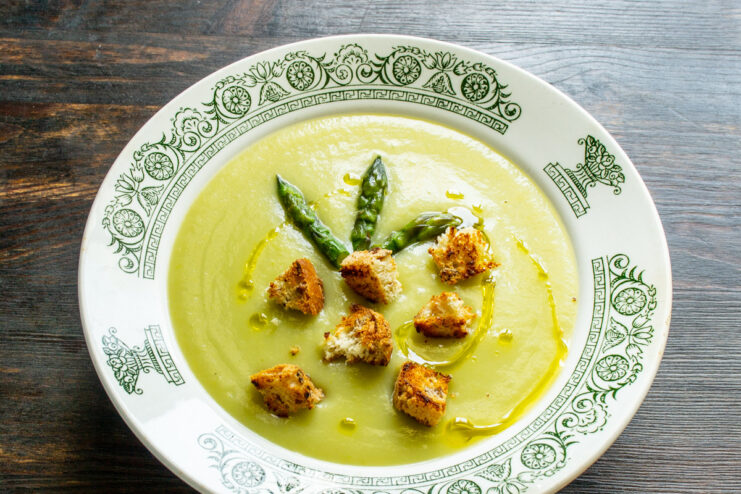The final presentation: Cream of Asparagus Soup with delicious toppings. A finished bowl of Cream of Asparagus Soup, garnished with asparagus tips and golden croutons.