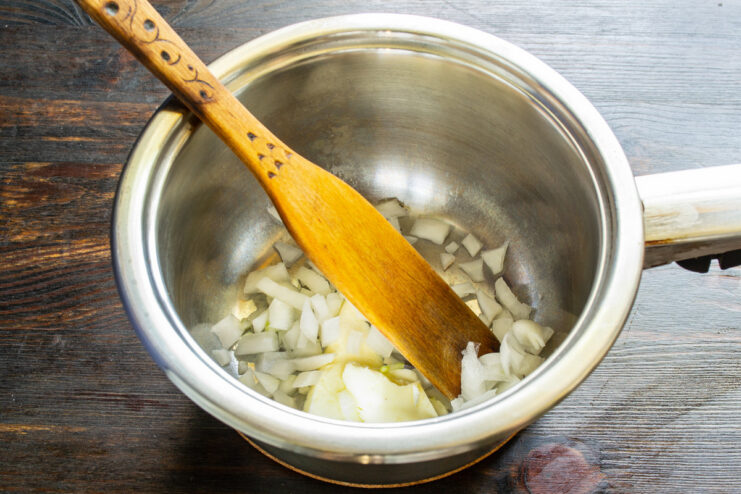 Finely dicing an onion, the first step for the soup base. A close-up of finely diced yellow onion on a cutting board.