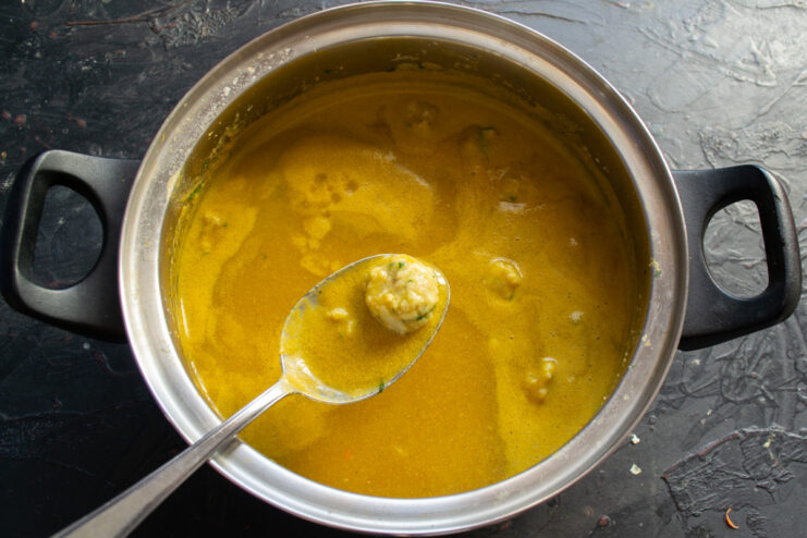 Hands forming small, round meatballs from a minced fish mixture.