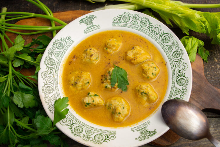 A bowl of creamy fish soup with meatballs, garnished with black pepper.