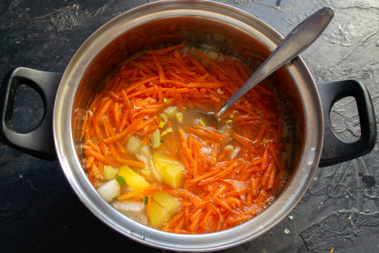 Fish broth being poured into a pot of chopped vegetables.
