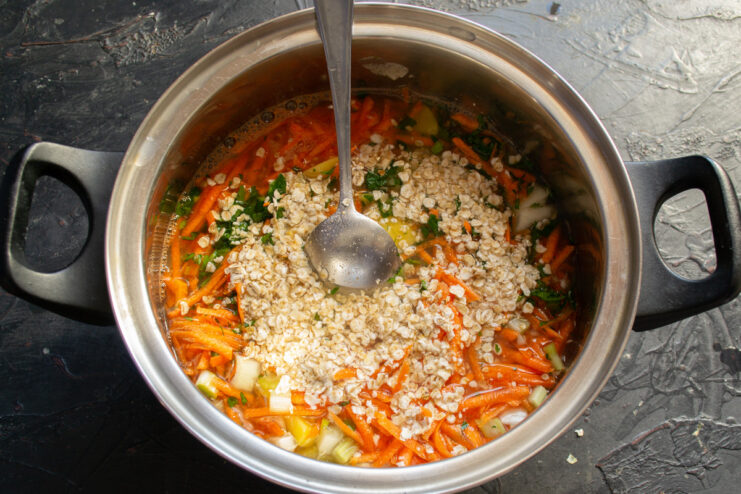 Quick-cooking rolled oats being poured into the soup pot.