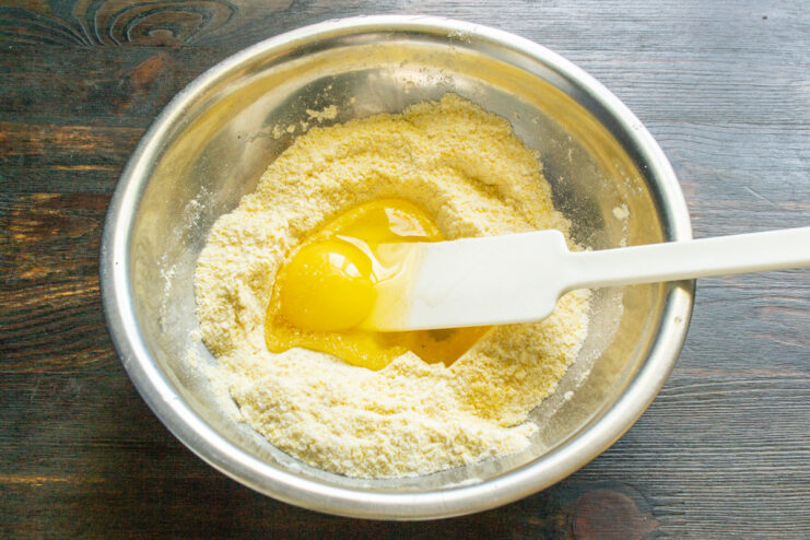 Adding Eggs to the Fritter Batter Two large chicken eggs cracked into a glass bowl.