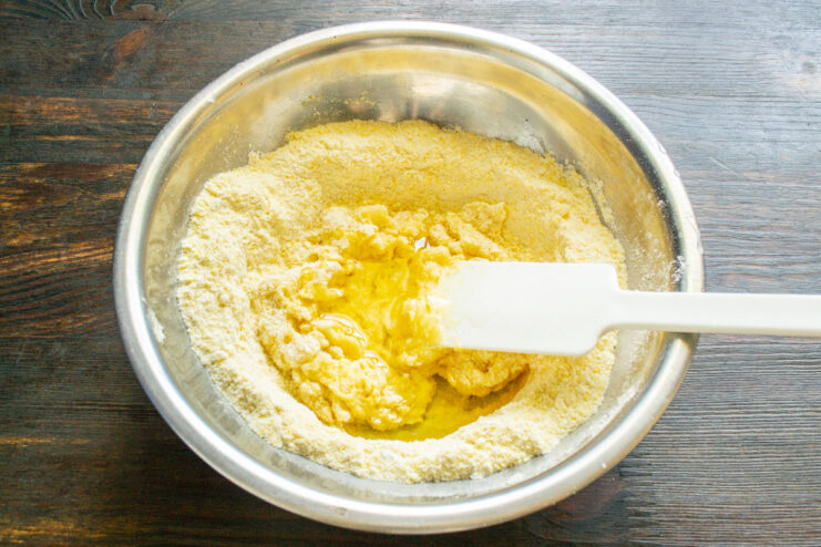 Pouring Olive Oil into the Batter Mix Olive oil being poured into a bowl with eggs for the fritter batter.