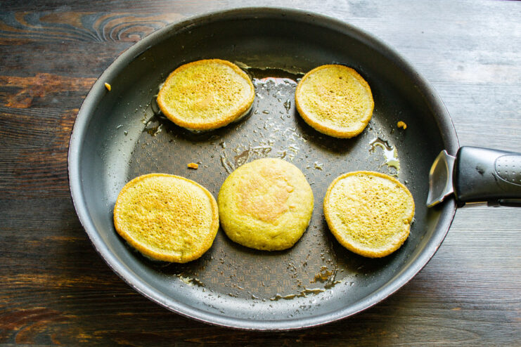 Flipping and Cooking the Other Side of the Fritters Corn fritters being flipped in a pan to cook the other side.