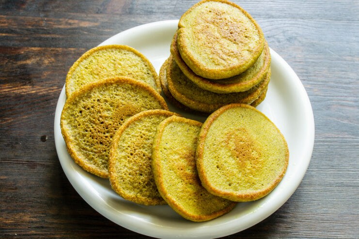Draining Excess Oil from Freshly Cooked Fritters Golden-brown cooked corn fritters resting on a paper towel to drain excess oil.
