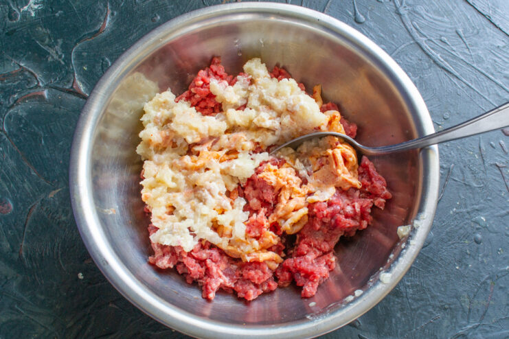 Step 3: Grinding Onion for Extra Flavor and Juiciness Diced onion being ground in a meat grinder after the meat and fat.