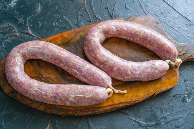 Finishing the Raw Kupaty Sausages Before Cooking Two freshly stuffed raw beef kupaty sausages, with their ends tied, ready for cooking.