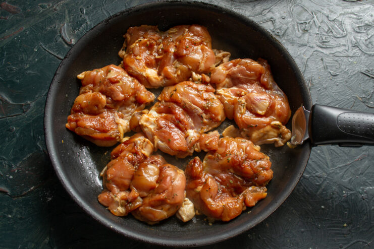 Searing the Chicken for a Crispy Golden Skin Marinated chicken thighs being placed skin-down onto a hot skillet.