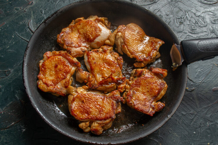 Achieving the Perfect Golden-Brown Crust on Chicken Flipping golden-brown chicken thighs in a skillet to cook the other side.