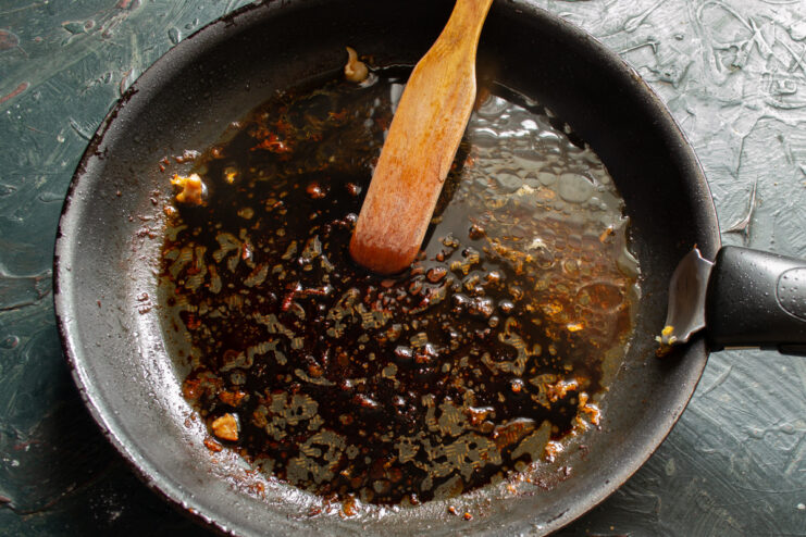 Using Pan Drippings to Create a Flavorful Sauce Cooked chicken thighs on a plate next to a skillet with pan drippings.