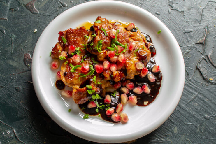 The Final Touch: Garnishing with Pomegranate and Cilantro Garnishing finished chicken in pomegranate sauce with fresh pomegranate seeds and cilantro.