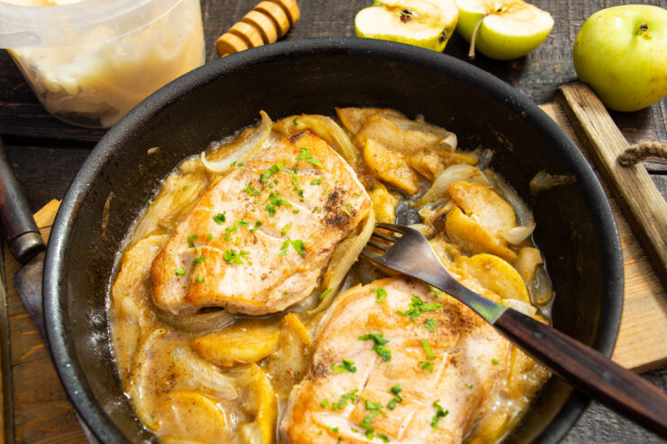 A plate of cooked chicken fillet with apples in honey-mustard sauce, garnished with parsley.