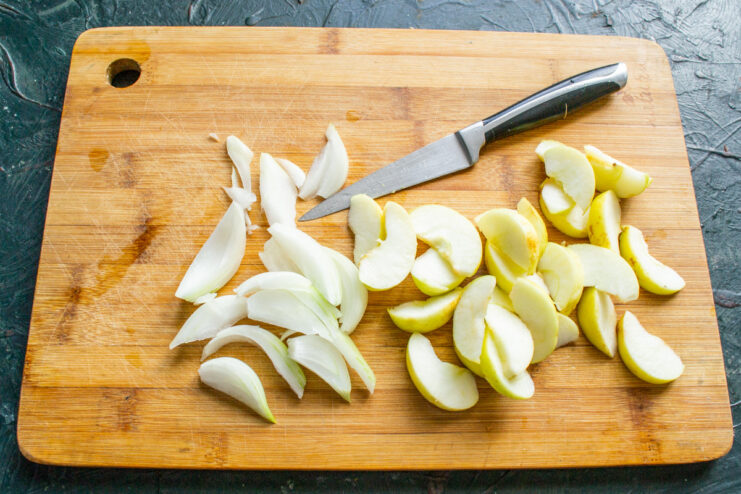 Slicing sweet-tart apples to pair with the chicken. Peeled apples being sliced into wedges on a cutting board.