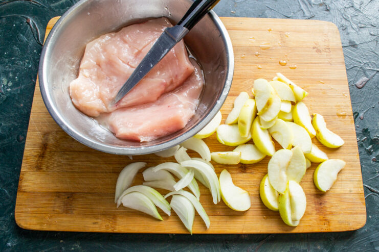 Scoring the chicken helps it cook evenly and absorb the sauce. Raw chicken breast with a criss-cross pattern scored into its surface.