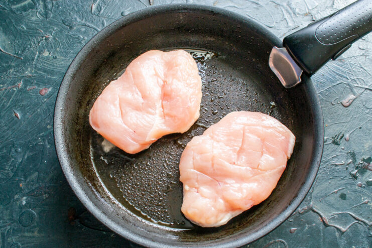 Searing the chicken to lock in the juices. Chicken breasts searing in a hot skillet to get a golden-brown crust.
