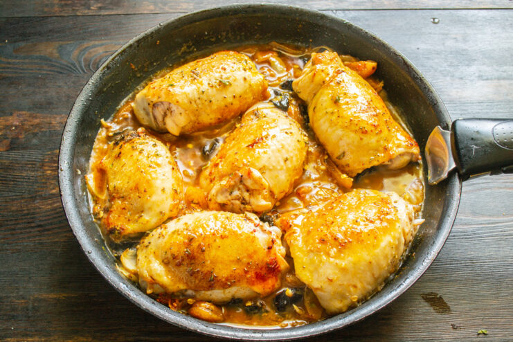 Creating the Braising Liquid Boiling water being poured into the skillet with chicken and spices.
