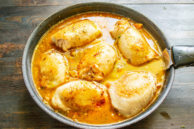 Bringing the Sauce to a Boil Before Baking The chicken and sauce in the skillet coming to a boil on the stovetop.