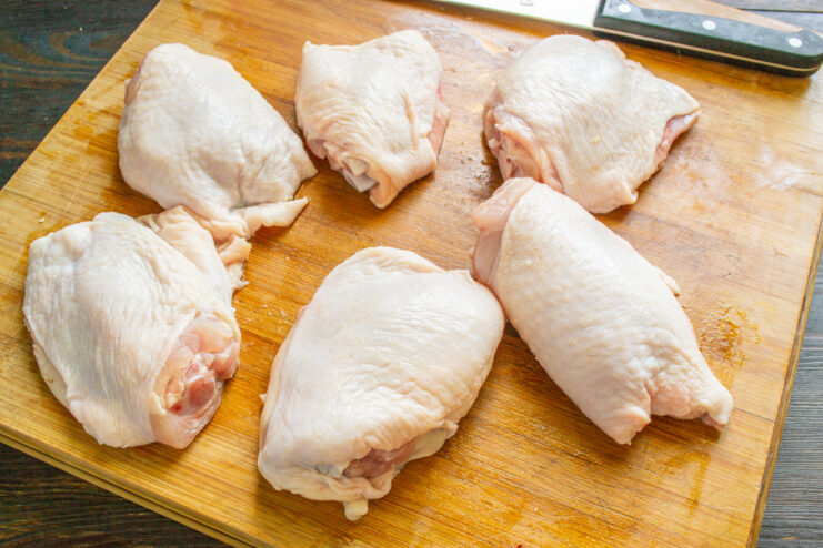 Step 1: Preparing the Chicken Thighs Raw chicken thighs being rinsed under cold water in a kitchen sink.