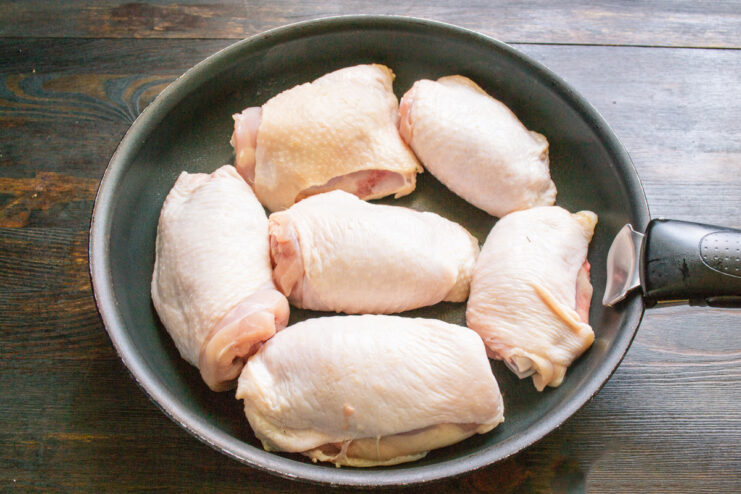 Searing the Chicken for a Crispy Skin Chicken thighs searing skin-down in a hot heavy-bottomed skillet.