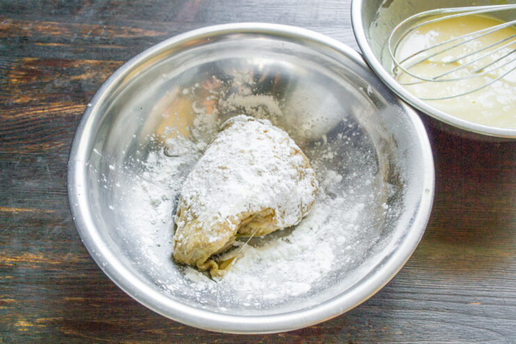 Boiled chicken thighs being coated in a thin layer of white starch.