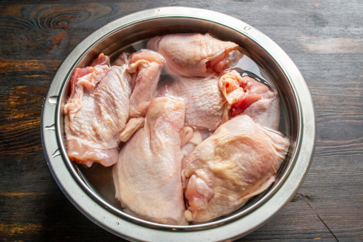 Preparing the Chicken Thighs for the Recipe Raw medium-sized chicken thighs on a cutting board.