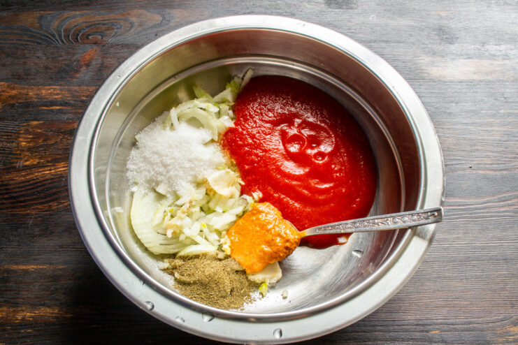 Adding Tomato Puree to the Sauce Base Adding thick tomato puree to the bowl with onion and garlic.