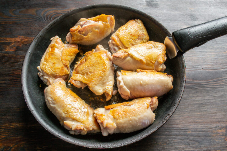 Searing the Other Side of the Chicken Thighs Flipping the golden-brown chicken thighs in the skillet.
