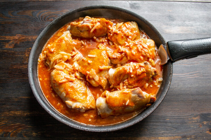 Covering the Chicken with Flavorful Tomato Sauce Pouring the prepared tomato sauce over the seared chicken thighs in the skillet.