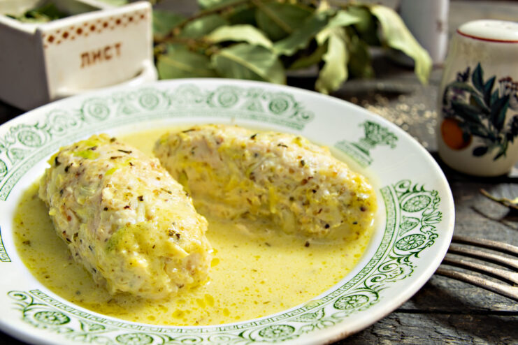 A white bowl filled with chicken and quinoa patties in a creamy yellow sauce, garnished with fresh herbs.