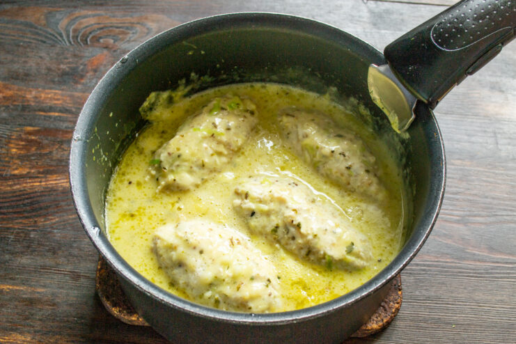 Simmering the patties in the sauce until cooked through Chicken patties simmering in a creamy sauce in a covered saucepan on the stove.